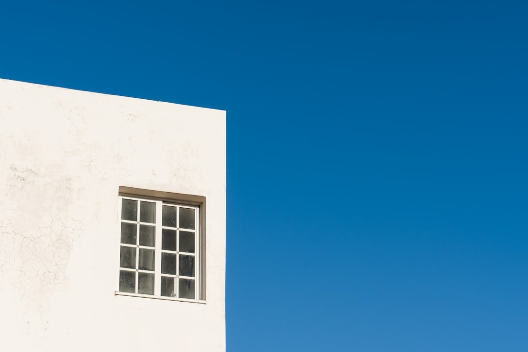 a white building with a window and a sky background