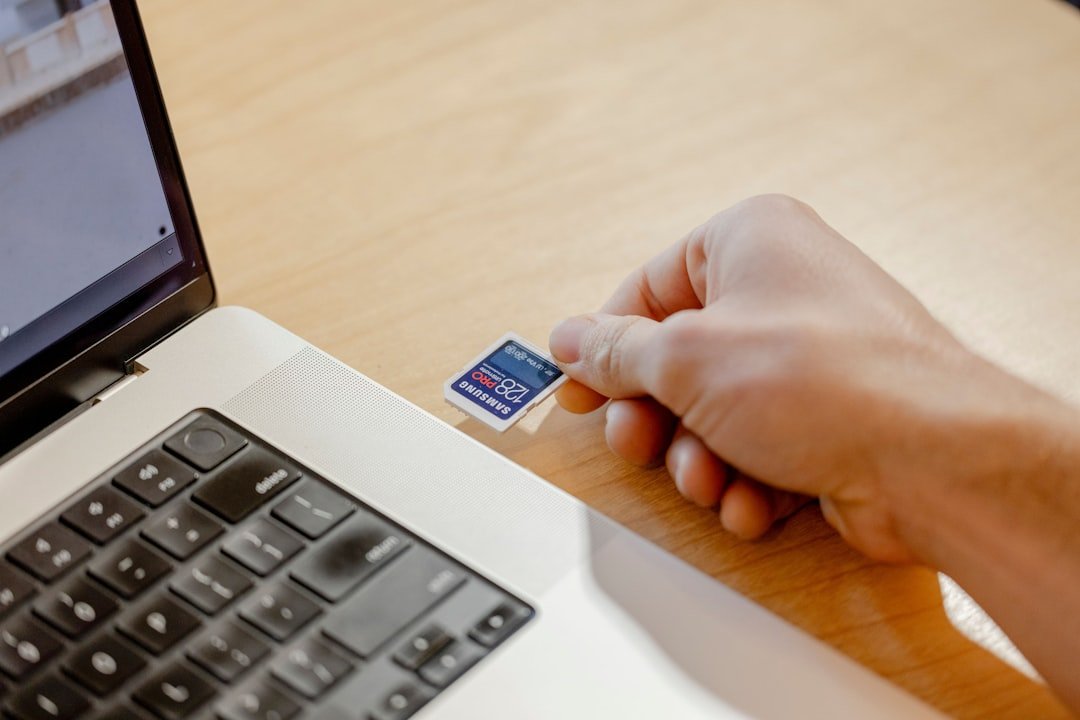 A person holding a credit card in front of a laptop