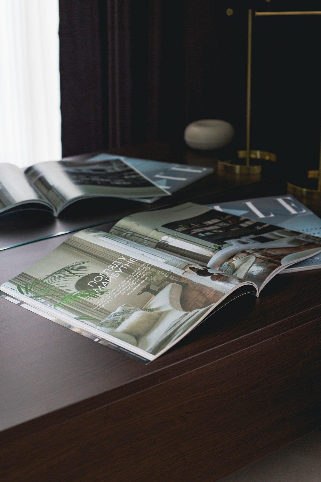 Magazines lay open on a dark wooden desk.