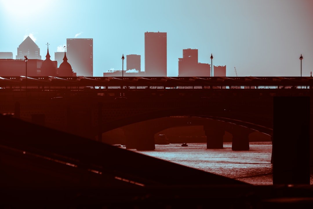 a bridge over a river with a city skyline in the background