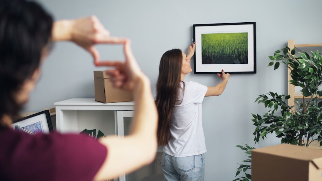 a woman standing in front of a picture hanging on a wall