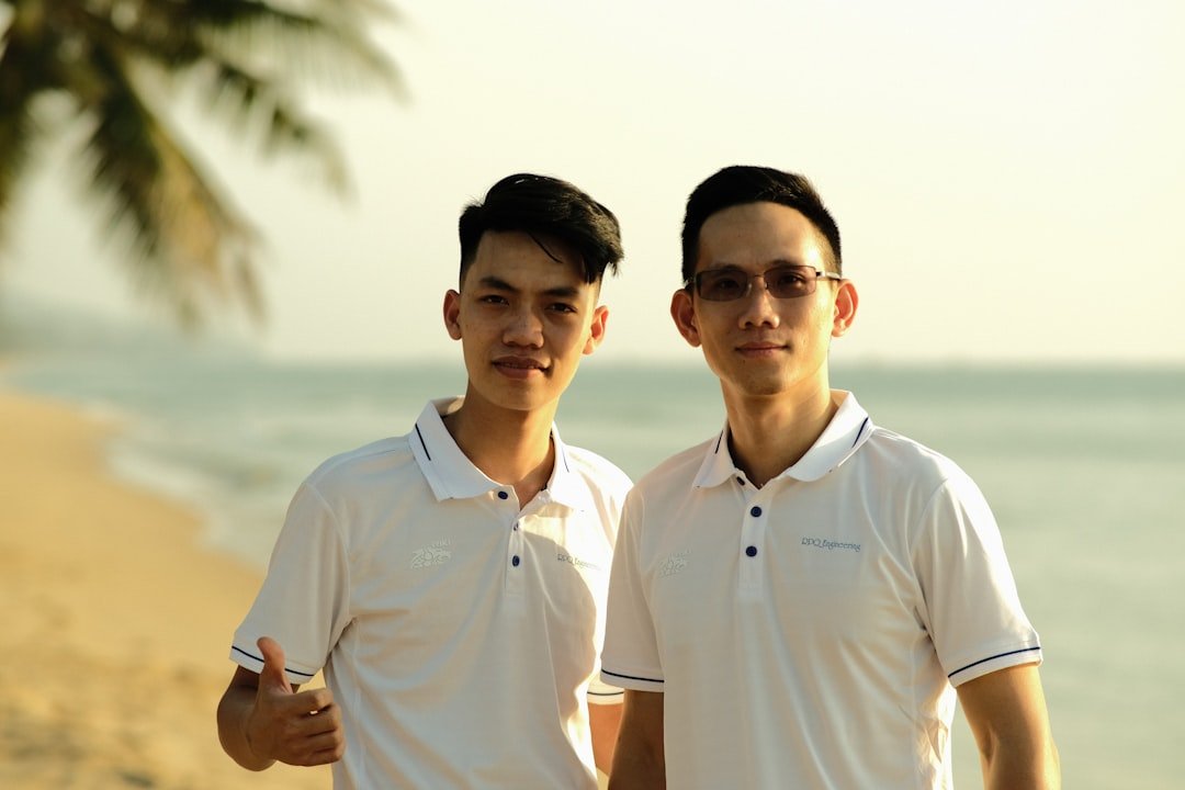 two men standing next to each other on a beach