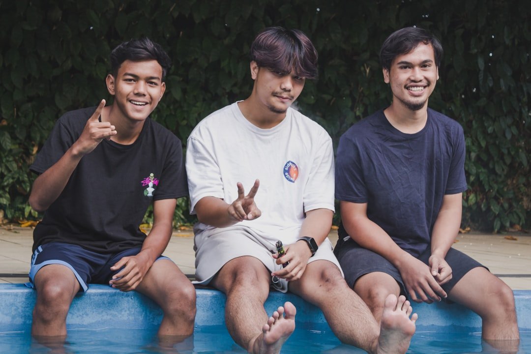 three men sitting in a pool with their fingers in the air